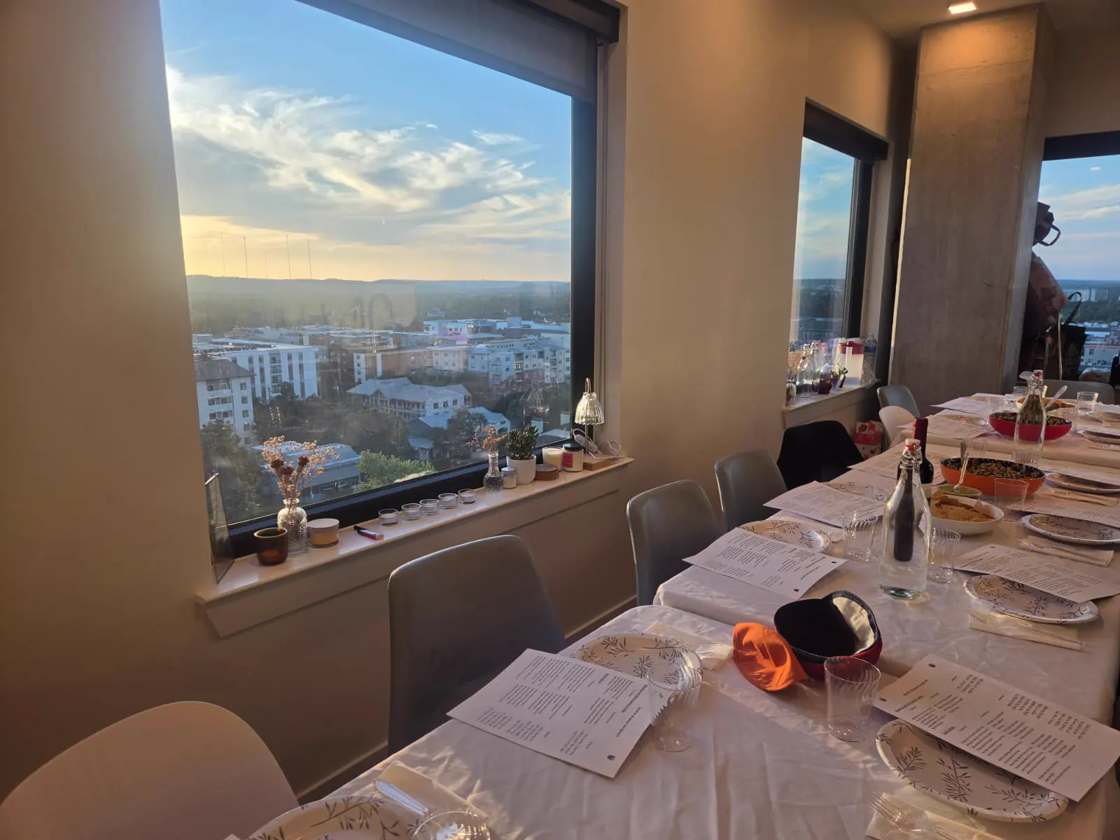 A long Shabbat table set beside a window at sunset